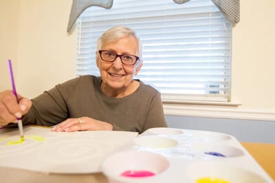 Senior resident painting in an activity room