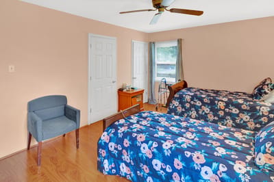 A bright interior room with two beds and a chair