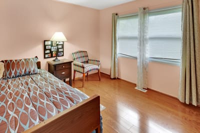 Brightly lit resident's bedroom with a bed and chair