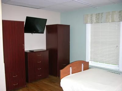 Interior view of a private resident room with a bed and dresser