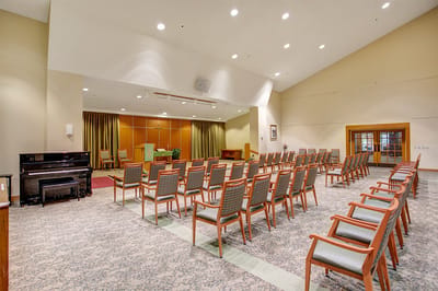 Bright activity room with rows of chairs and a piano