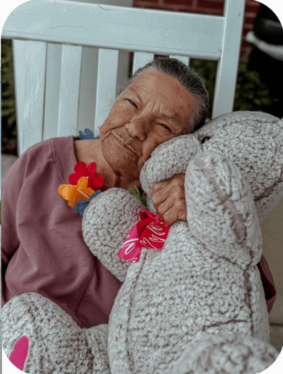 Resident affectionately holding a large teddy bear