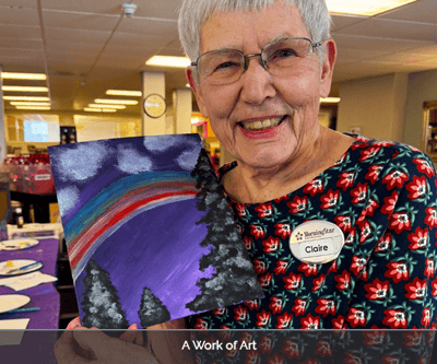Resident showcasing their artwork in the activity room