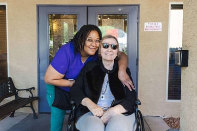 Staff member with a resident outdoors in front of the facility