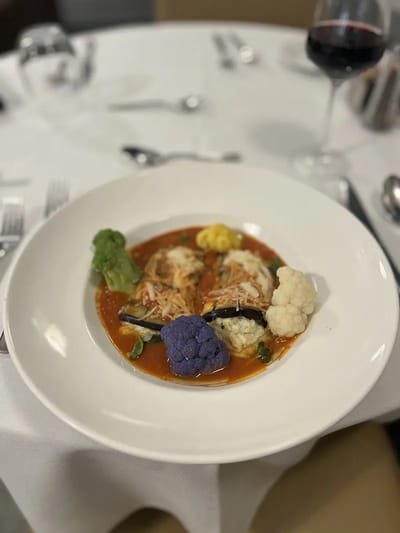 Plate of pasta with vegetables and wine on dining table
