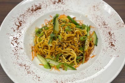 Plate of noodle dish with vegetables and sesame seeds