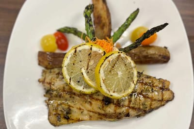 Grilled fish dish garnished with vegetables