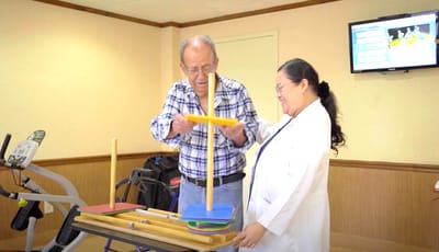 Staff assisting a resident with an activity in a therapy room