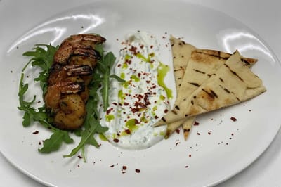 A gourmet plate with grilled shrimp and pita bread