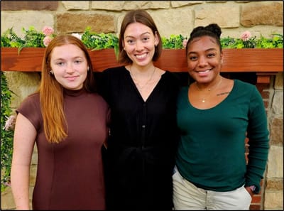 Three staff members smiling in a welcoming environment