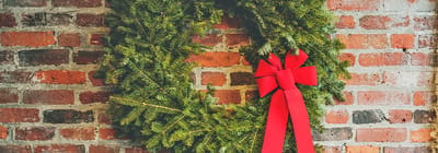 Festive wreath with red bow on a brick wall