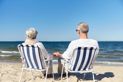 Elderly couple sitting on beach chairs by the water