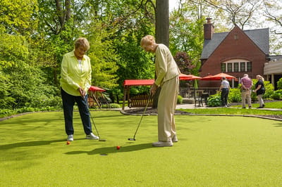 Two residents playing mini-golf in a garden area