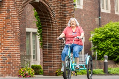 Resident riding a tricycle near a brick archway