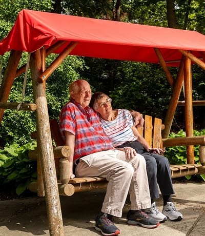 Two residents enjoying a swing in a garden