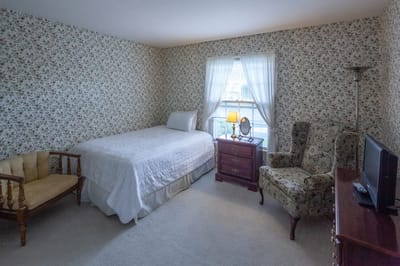Cozy private room with floral wallpaper and furniture.