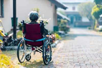 Senior woman in a wheelchair on a pathway.