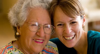 Senior woman and caregiver smiling together.