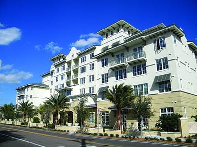 Exterior view of a senior living facility with palm trees