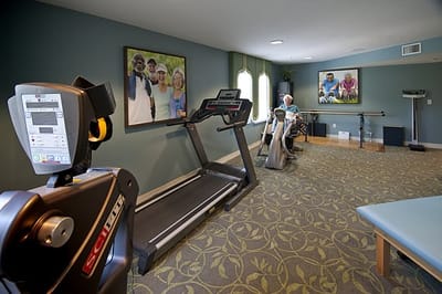Residents exercising in a fitness room with equipment