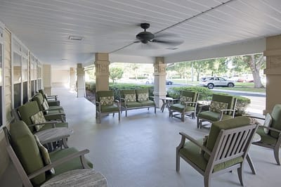 Covered outdoor seating area with green chairs