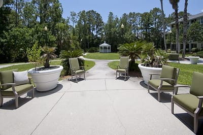 Outdoor seating area with palm trees and gazebo in the background