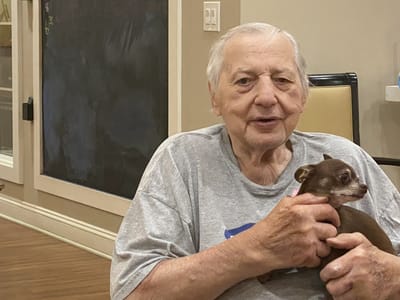 Elderly man holding a small dog in a cozy indoor setting