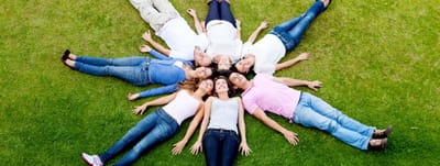 Group of people lying on the grass in a circle