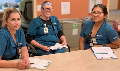 Three staff members smiling at a table in the facility