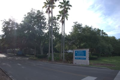 Entrance to Tampa Gardens Senior Living with palm trees