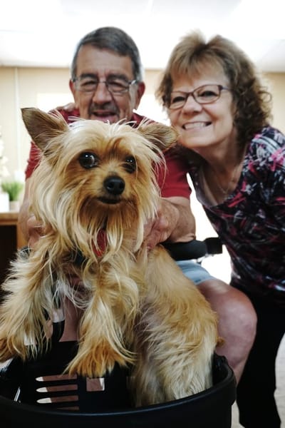 Residents smiling with a small dog in a cozy interior