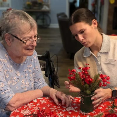 Resident and staff member arranging flowers together.
