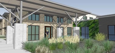 Building entrance with landscaping and a person standing