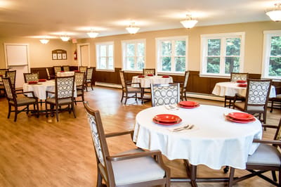 Bright dining room with round tables and red plates.