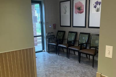 Seating area with floral art and a walker.