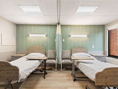 Shared room with two hospital beds and seating area.