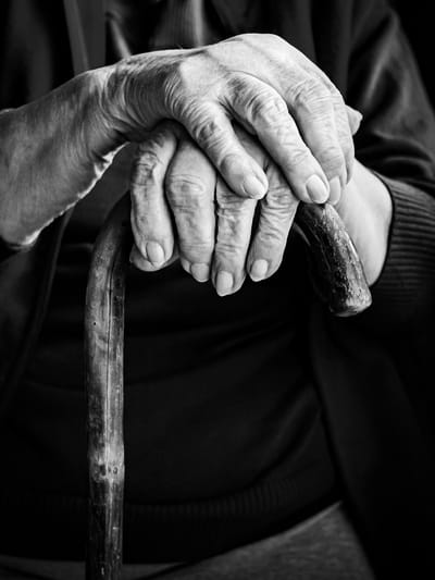 Close-up of elderly hands on a cane
