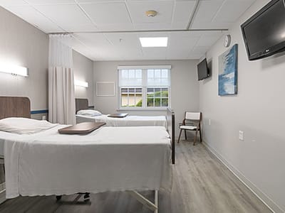 Standard resident room with two beds and windows.