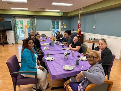 Residents and staff enjoying a gathering around a table.