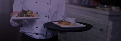 Server presenting plated meals in a dining setting.
