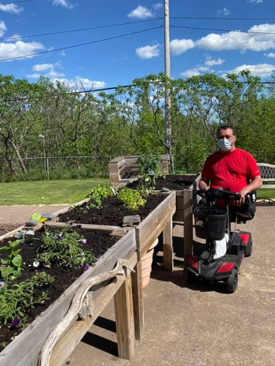 Resident gardening with a mobility scooter.