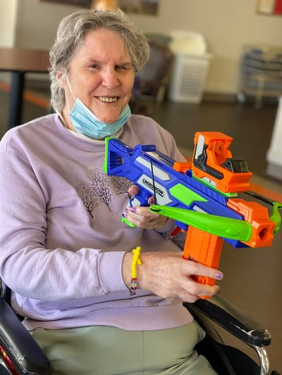 Senior resident enjoying an activity with a toy gun.
