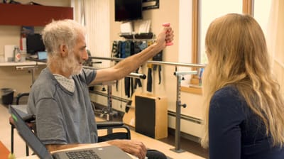 Resident engaging in therapy with staff assistance.