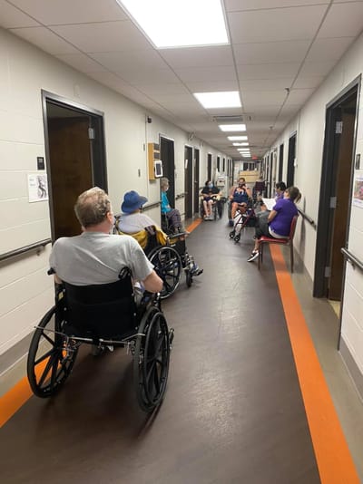 Residents seated in a hallway with wheelchairs