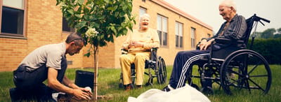 Residents enjoying outdoor activity planting a tree.
