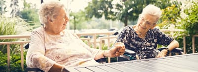 Two elderly women enjoying a conversation outdoors.