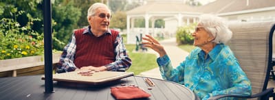 Two seniors engaged in conversation outdoors.