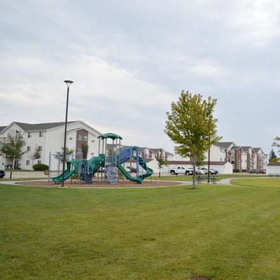 Playground area with green grass and buildings in the background.