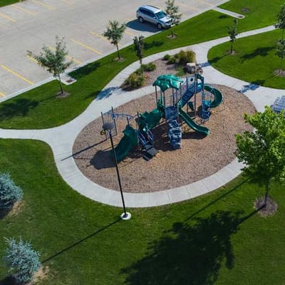 Playground area with grass, trees, and pathways.