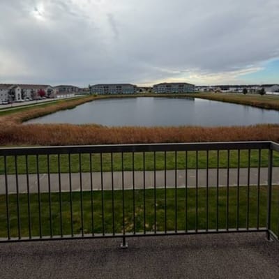 View of a pond and nearby buildings from a balcony.